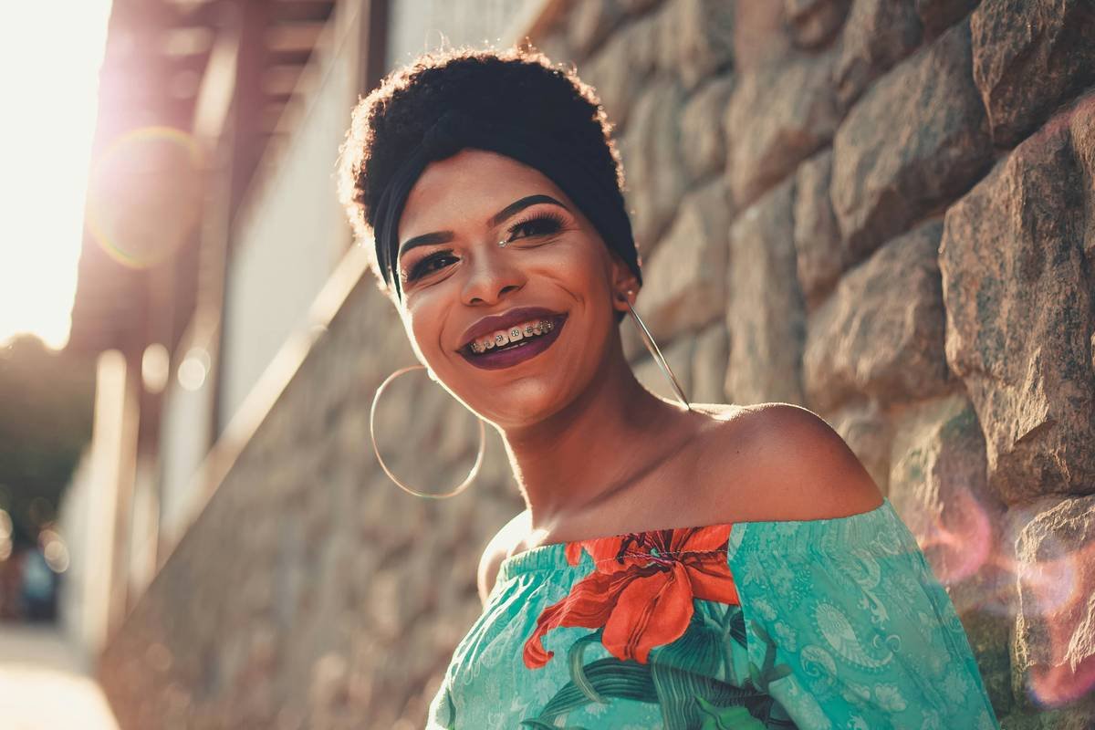 smiling woman leaning on brick wall